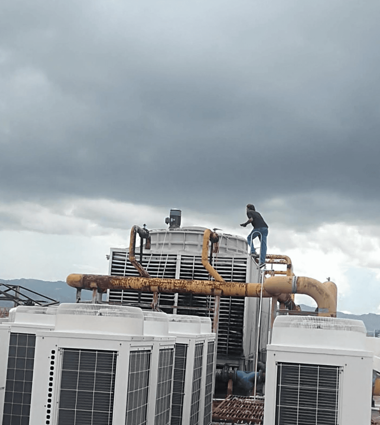 Technician performing cooling tower maintenance on a rooftop system
